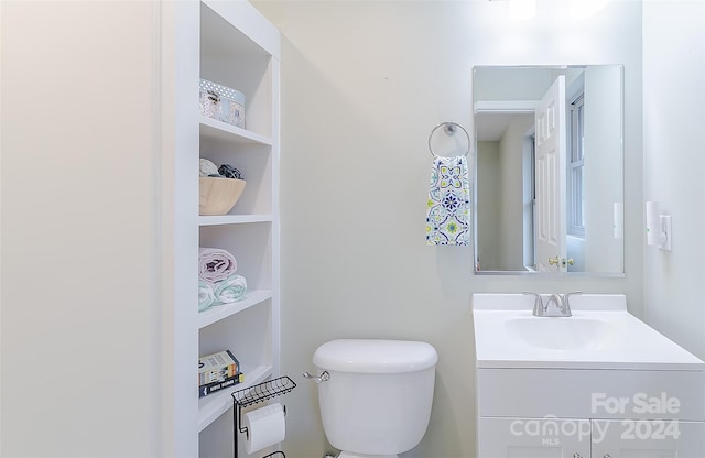 bathroom with vanity with extensive cabinet space, built in shelves, and toilet