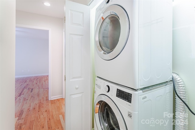 laundry room featuring light wood-type flooring and stacked washing maching and dryer