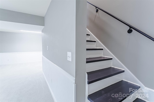 stairway featuring light carpet