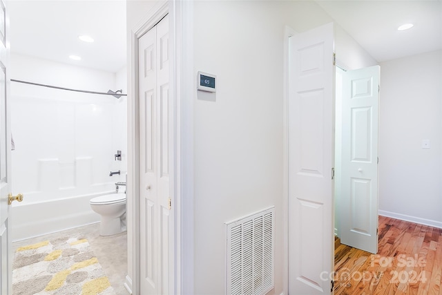 bathroom featuring wood-type flooring,  shower combination, and toilet