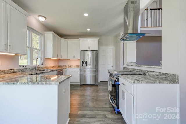 kitchen with white cabinets, light stone countertops, island range hood, hardwood / wood-style floors, and appliances with stainless steel finishes