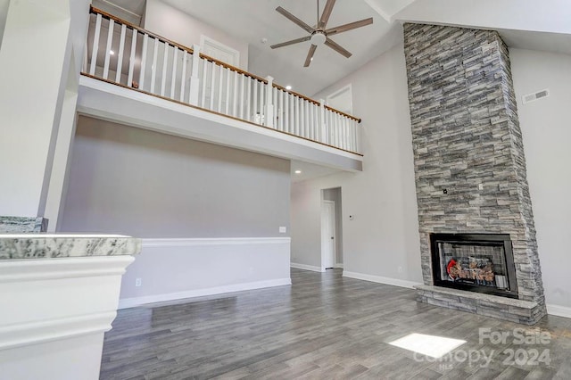 unfurnished living room with a stone fireplace, high vaulted ceiling, ceiling fan, and hardwood / wood-style floors