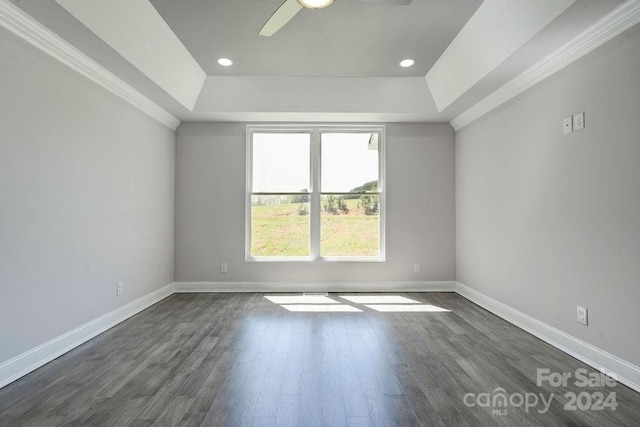 empty room with dark hardwood / wood-style floors, a raised ceiling, and ceiling fan