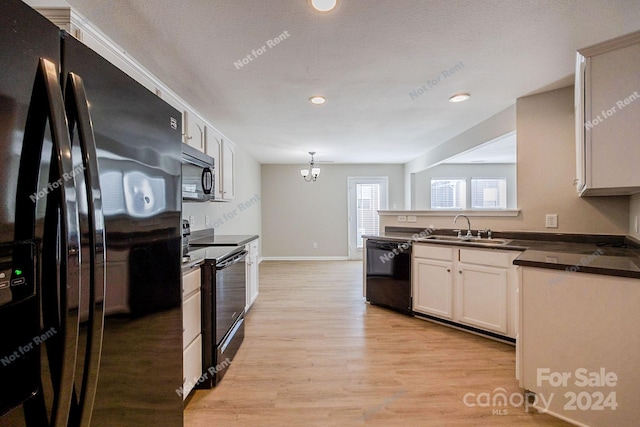 kitchen featuring sink, light hardwood / wood-style floors, black appliances, decorative light fixtures, and a notable chandelier