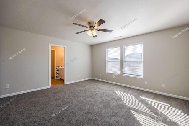 unfurnished bedroom with ceiling fan, ensuite bathroom, and dark colored carpet