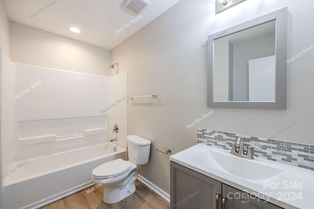 full bathroom with vanity, hardwood / wood-style floors, bathtub / shower combination, toilet, and tasteful backsplash