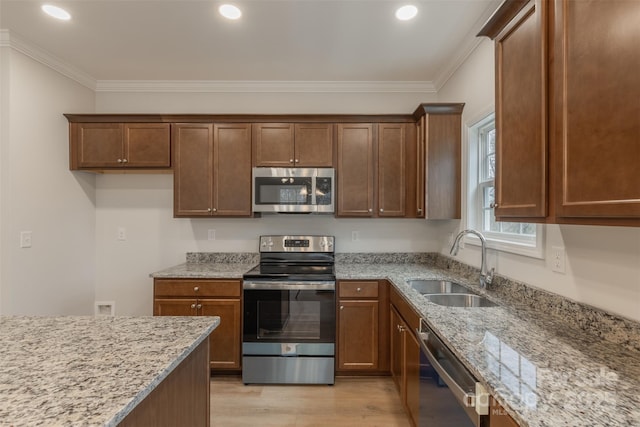 kitchen featuring light stone countertops, light wood-type flooring, stainless steel appliances, crown molding, and sink