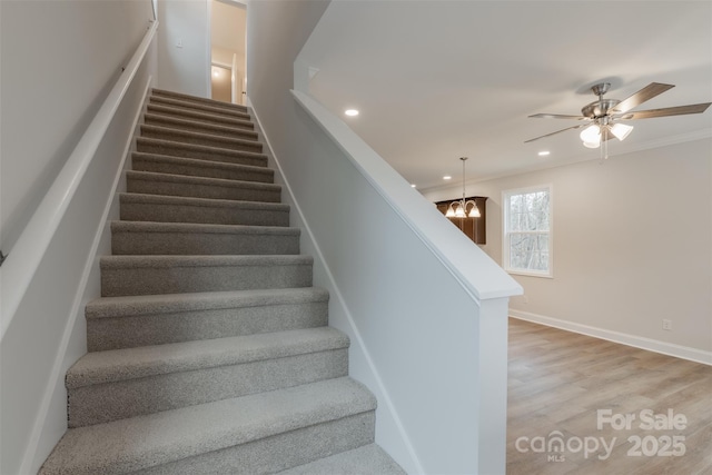 stairs featuring wood-type flooring and ceiling fan with notable chandelier