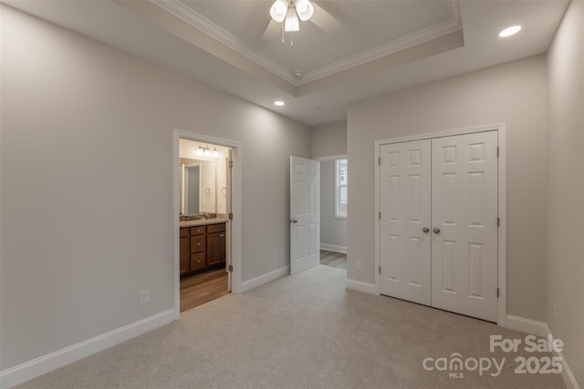 unfurnished bedroom featuring light carpet, a raised ceiling, crown molding, ceiling fan, and a closet