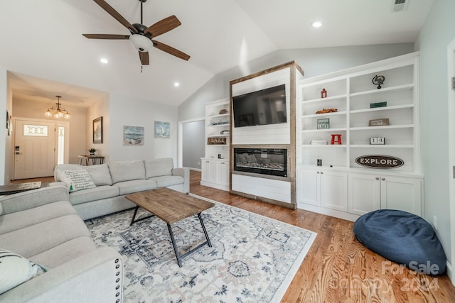 living room featuring built in features, light hardwood / wood-style floors, ceiling fan with notable chandelier, and lofted ceiling