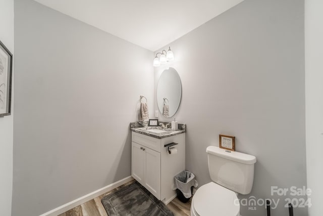 bathroom with toilet, wood-type flooring, and vanity