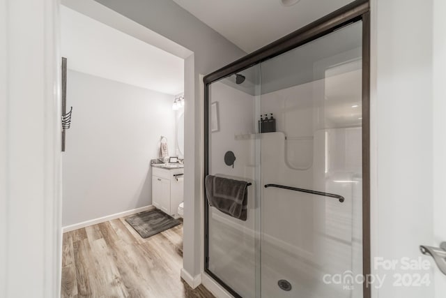 bathroom with vanity, toilet, a shower with door, and hardwood / wood-style flooring