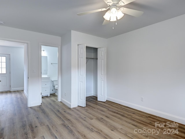 unfurnished bedroom featuring a closet, light wood-type flooring, ensuite bathroom, and ceiling fan