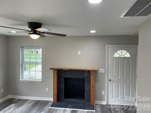 unfurnished living room featuring dark hardwood / wood-style flooring, ceiling fan, and a tiled fireplace