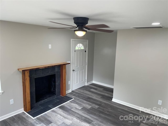 unfurnished living room featuring ceiling fan, a tile fireplace, and dark hardwood / wood-style floors