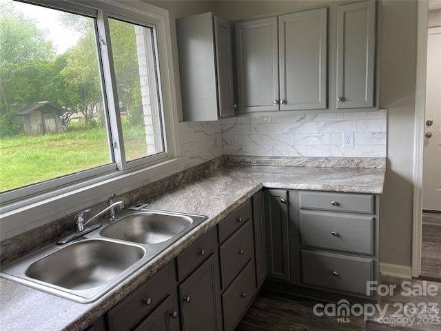 kitchen featuring plenty of natural light, tasteful backsplash, gray cabinets, and sink