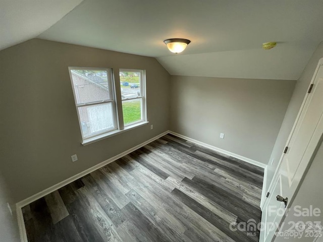 spare room featuring dark hardwood / wood-style floors and vaulted ceiling