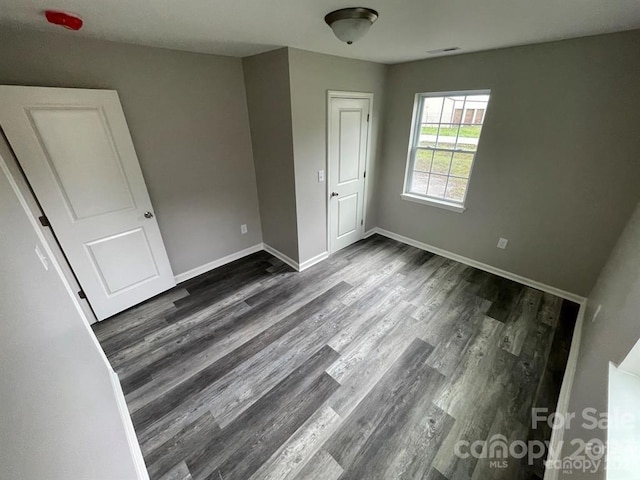 unfurnished room with dark wood-type flooring