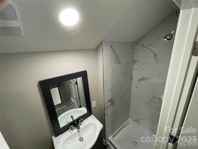 bathroom with tiled shower and oversized vanity