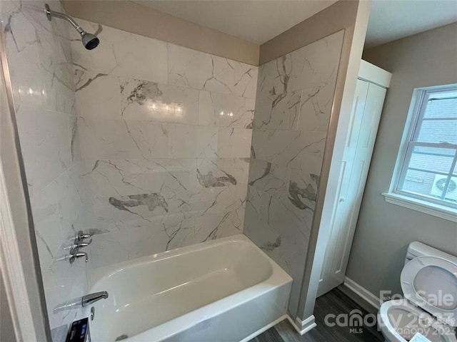 bathroom featuring tiled shower / bath combo, toilet, and wood-type flooring