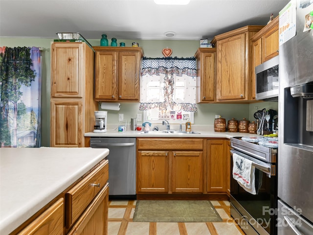 kitchen with appliances with stainless steel finishes, sink, and light tile floors