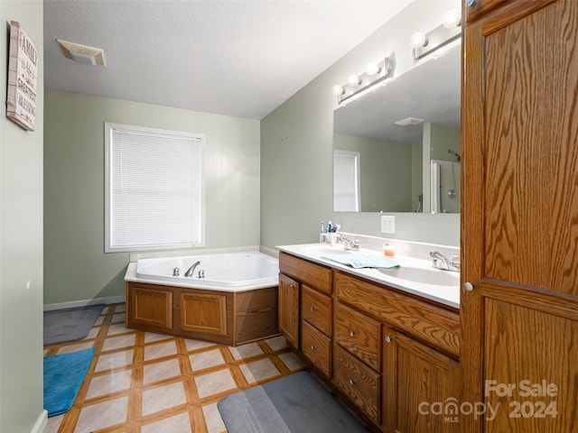 bathroom with a bath, a textured ceiling, double sink vanity, and tile flooring