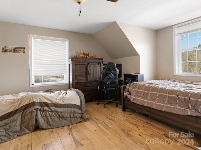 bedroom with ceiling fan, light wood-type flooring, and vaulted ceiling