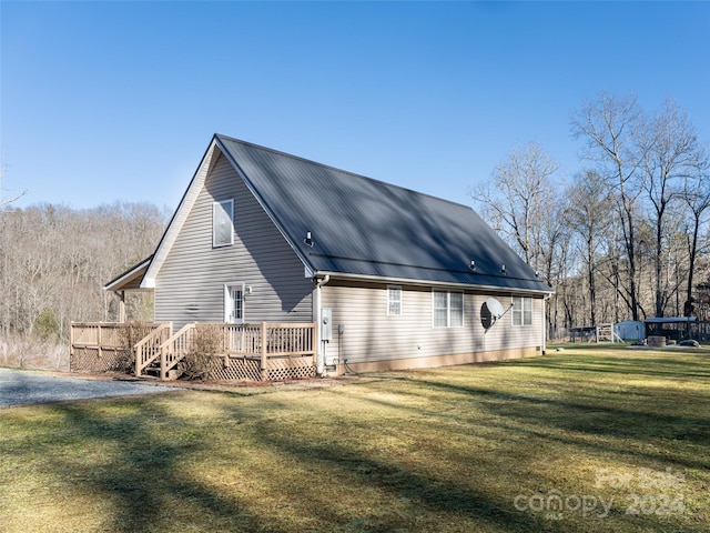 rear view of property featuring a wooden deck and a lawn