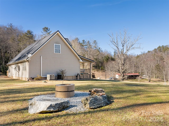 view of property exterior with central AC unit and a yard