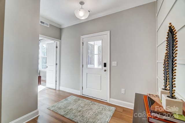 foyer entrance featuring ornamental molding and light hardwood / wood-style flooring