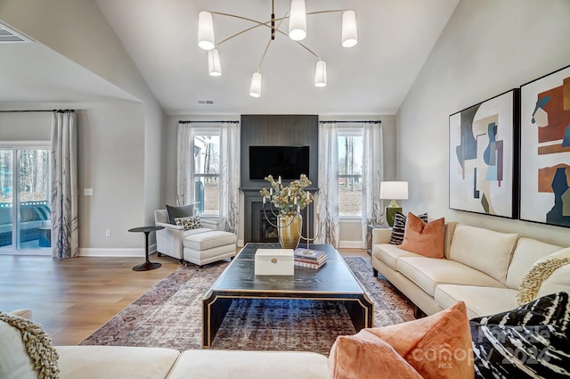 living room featuring vaulted ceiling, hardwood / wood-style flooring, and an inviting chandelier