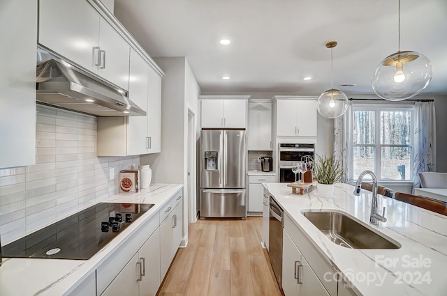 kitchen featuring hanging light fixtures, backsplash, light wood-type flooring, and stainless steel appliances