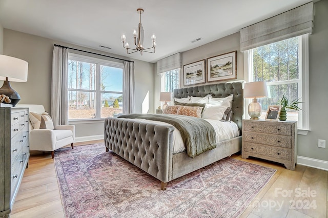 bedroom with light hardwood / wood-style floors, a chandelier, and multiple windows