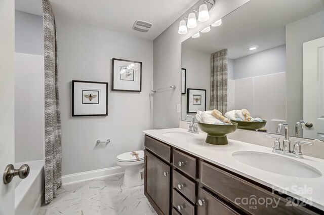 bathroom with tile floors, toilet, and dual bowl vanity