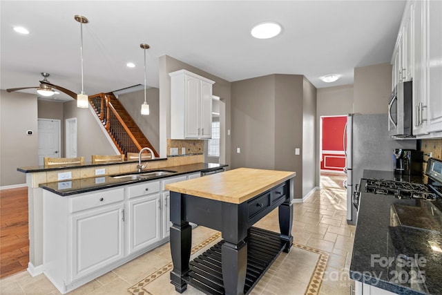 kitchen featuring pendant lighting, sink, white cabinetry, a center island, and kitchen peninsula