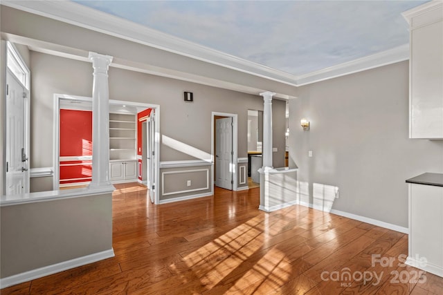 unfurnished living room featuring crown molding, wood-type flooring, and ornate columns