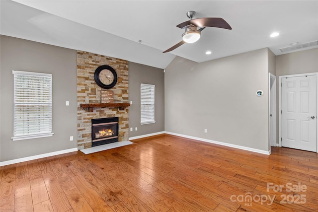 unfurnished living room with ceiling fan, a fireplace, and light wood-type flooring