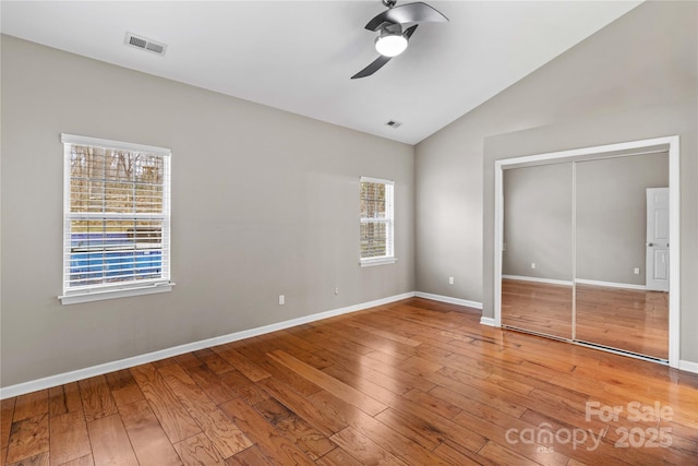 unfurnished bedroom with multiple windows, ceiling fan, hardwood / wood-style floors, and a closet