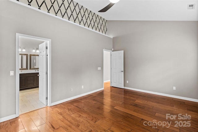 empty room featuring a towering ceiling, light hardwood / wood-style floors, and ceiling fan