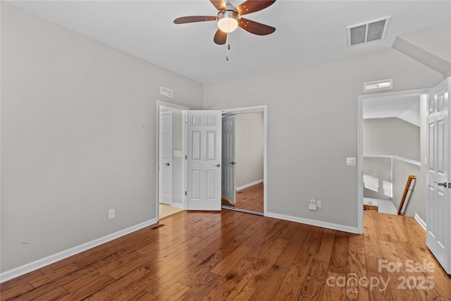 unfurnished bedroom featuring lofted ceiling, wood-type flooring, a closet, and ceiling fan