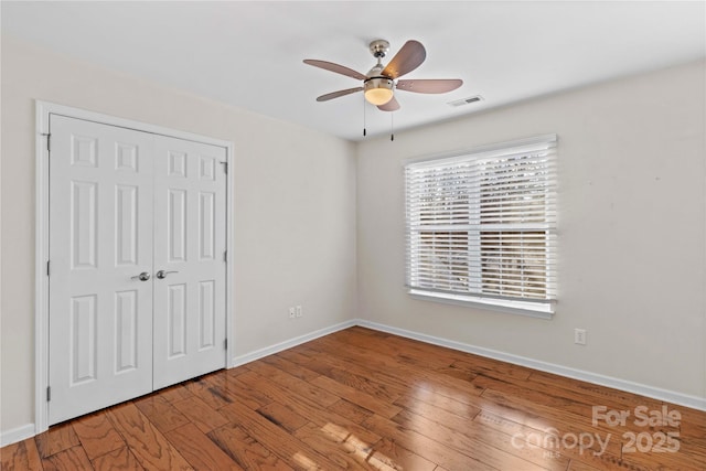 unfurnished bedroom with hardwood / wood-style floors, a closet, and ceiling fan