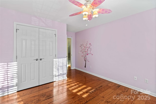 unfurnished bedroom featuring hardwood / wood-style flooring, ceiling fan, and a closet