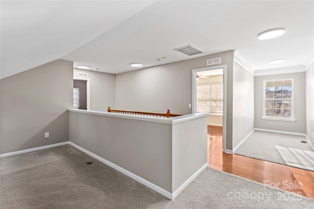 hallway featuring ornamental molding, vaulted ceiling, and light carpet