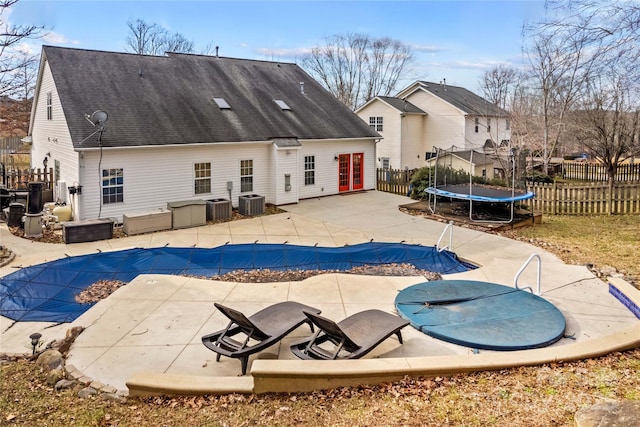 view of pool with a trampoline, cooling unit, a patio, and french doors