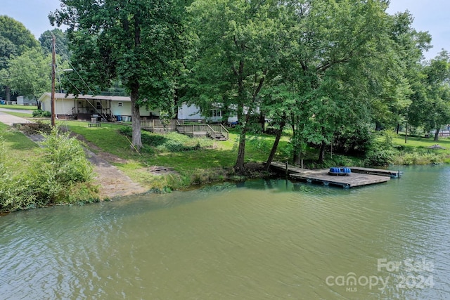 view of dock with a lawn and a water view