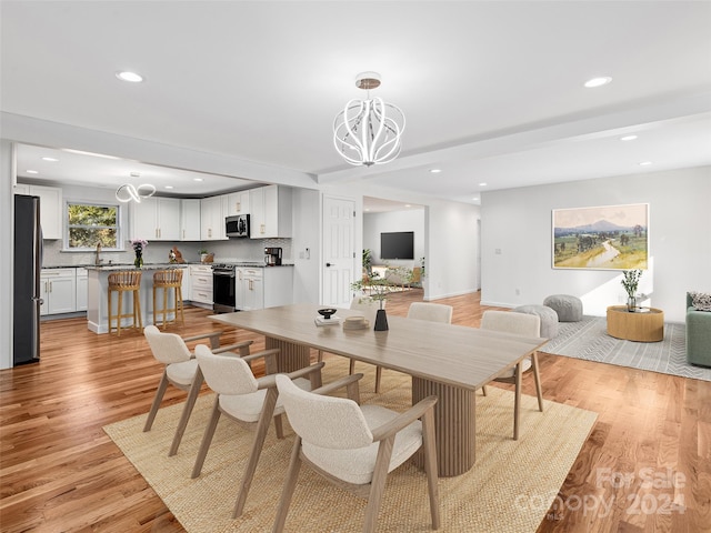 dining room with beam ceiling, light wood-type flooring, sink, and a chandelier