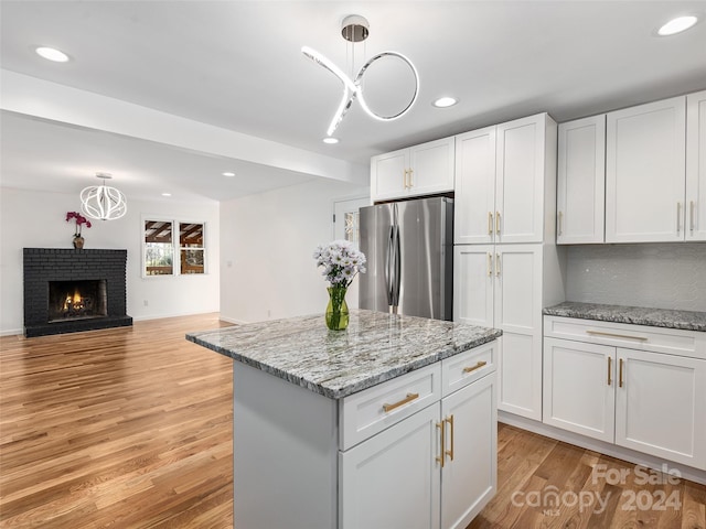 kitchen featuring white cabinets, light wood-type flooring, stainless steel fridge, and pendant lighting