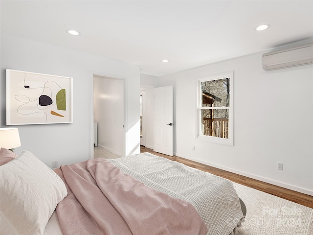 bedroom featuring light wood-type flooring and an AC wall unit