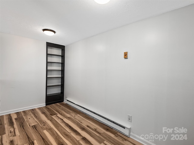 spare room with wood-type flooring, a textured ceiling, and a baseboard radiator