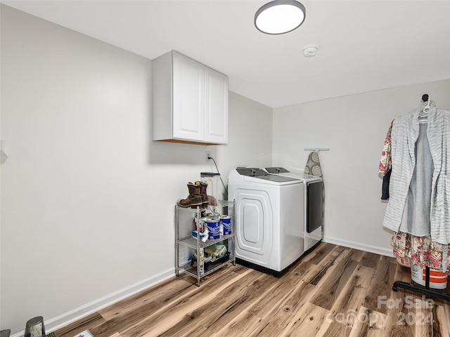 clothes washing area featuring cabinets, wood-type flooring, and washer and clothes dryer